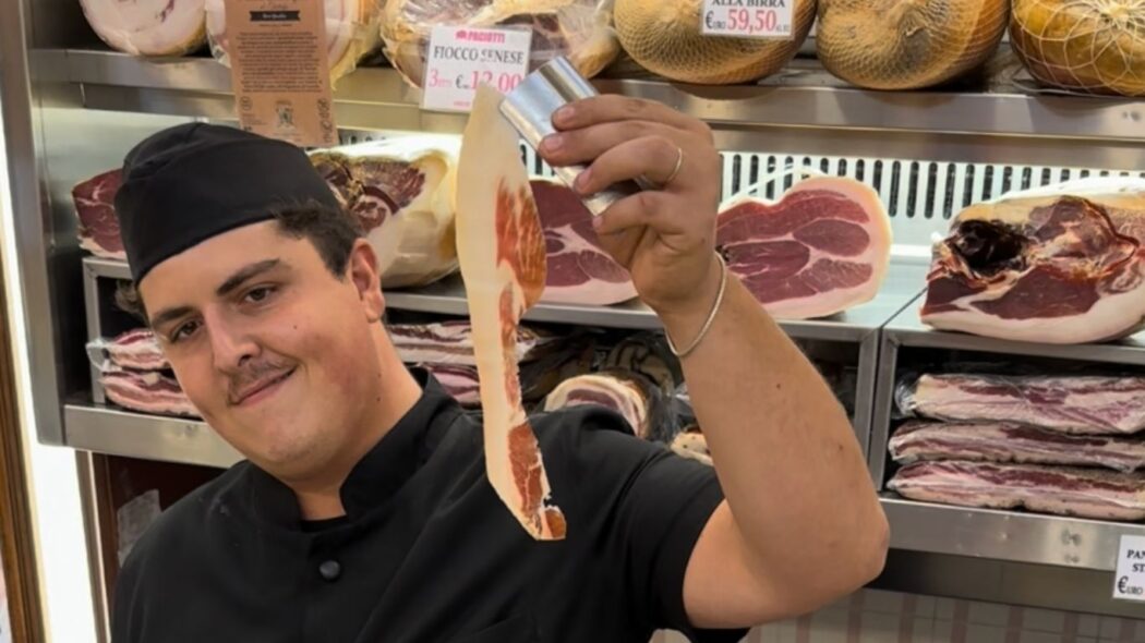 Man holding traditional cured ham at a delicatessen in Rome, Italy