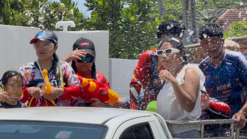 Thai family with water guns riding in the back of a pickup truck during Songkran water festival in Koh Samui 2026