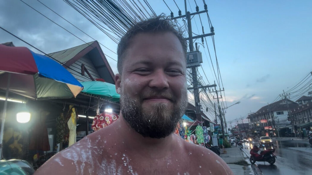 Happy traveler smiling after Songkran water festival celebrations in Koh Samui, Thailand 2026, wet from head to toe at dusk
