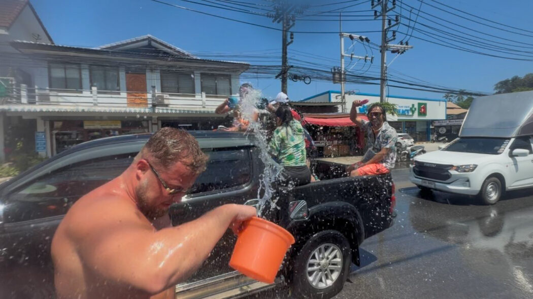 Tourist throwing water from a bucket during Songkran street water fight in Lamai, Koh Samui, Thailand 2026