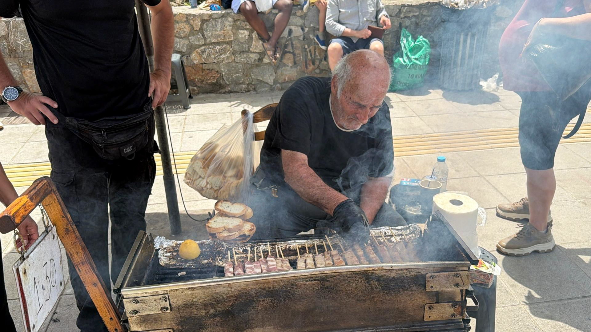 Local man grilling souvlaki skewers at the Chania Saturday market street food stall