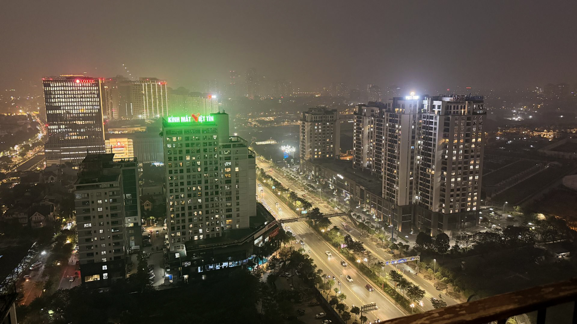 Night skyline of Hanoi, Vietnam with illuminated high-rise buildings and busy city streets.