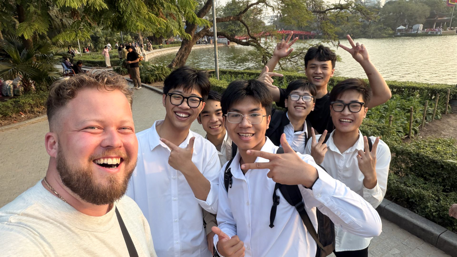 Traveler meeting local students near Hoan Kiem Lake in Hanoi, Vietnam.