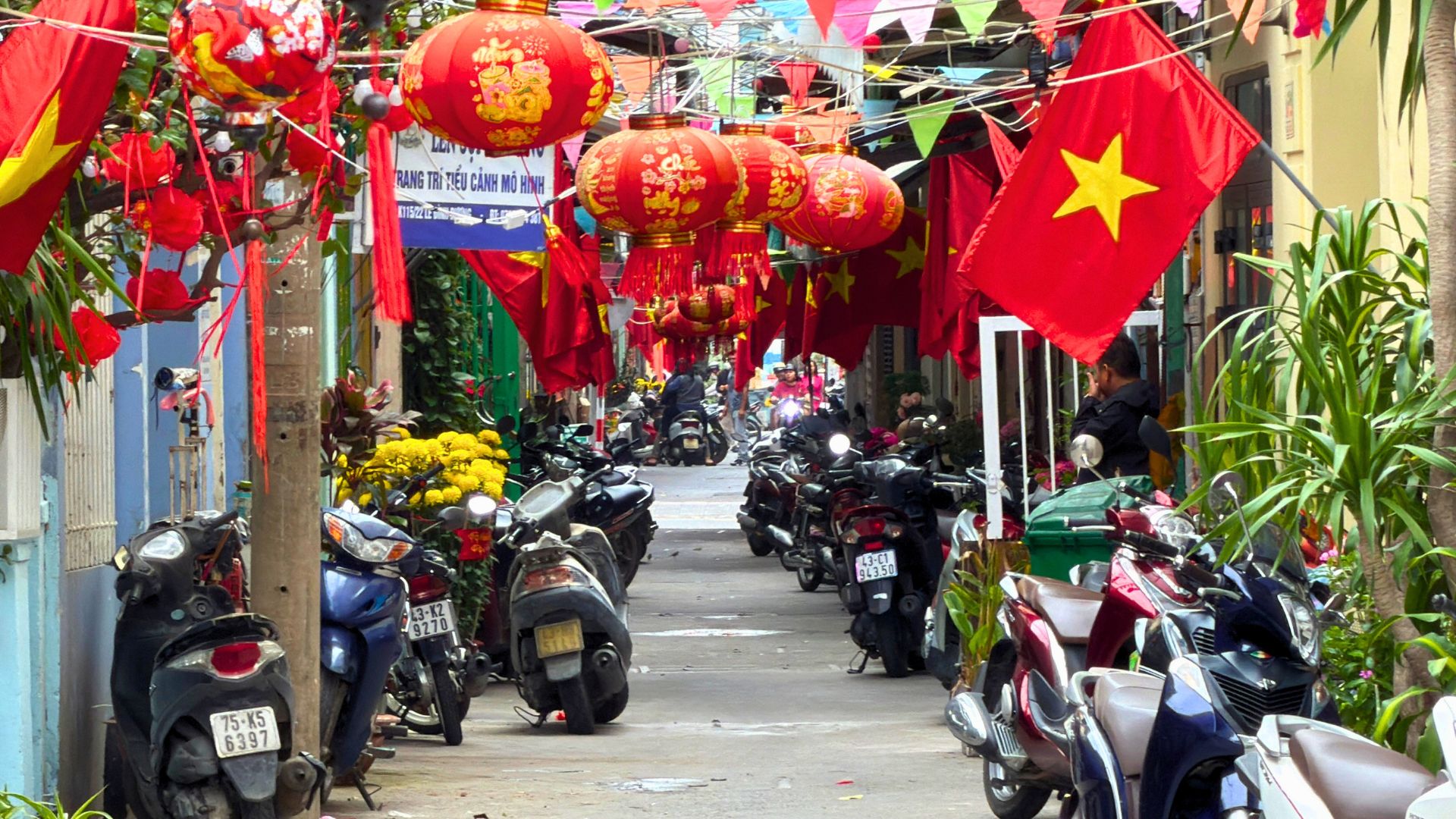 Narrow street in Da Nang decorated with Vietnamese flags and red lanterns for Tet Lunar New Year.